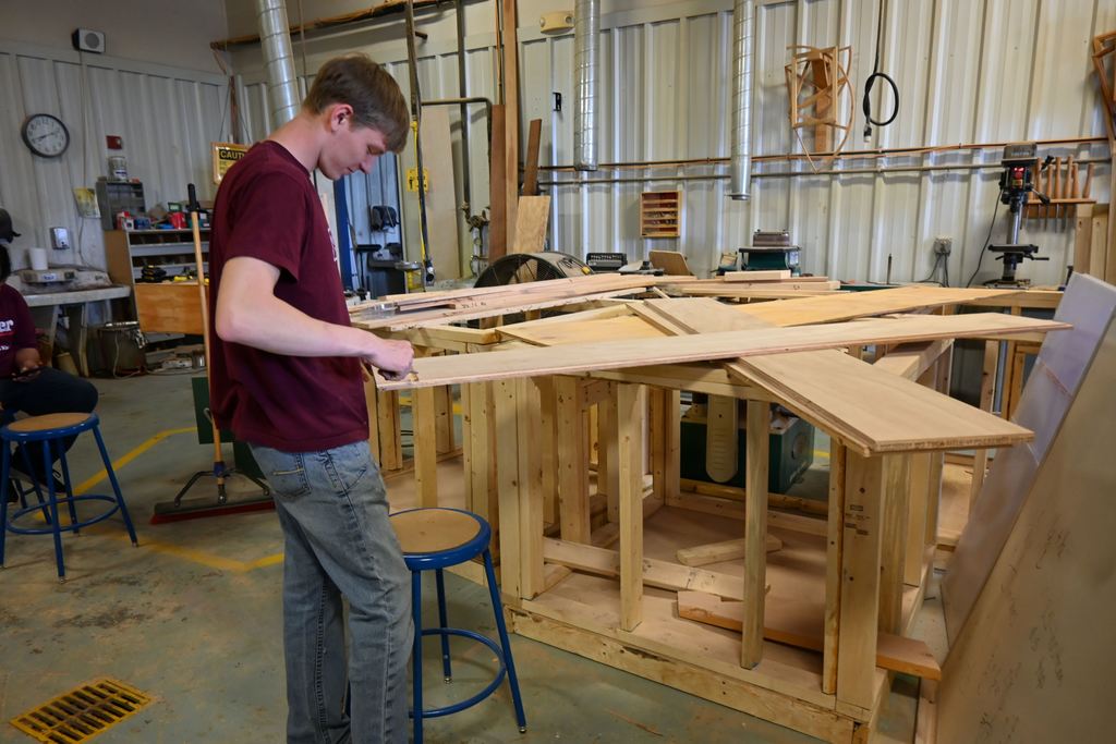 A construction student works on building a book case for the library.