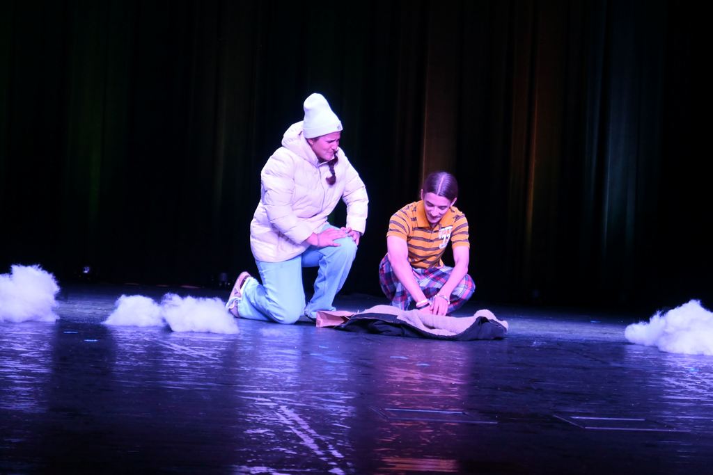 A man kneels down to wotk on something and a woman kneels next to him.