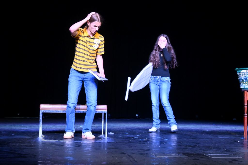A man rubs his head after being hit accidentally by a woman with an ironing board.