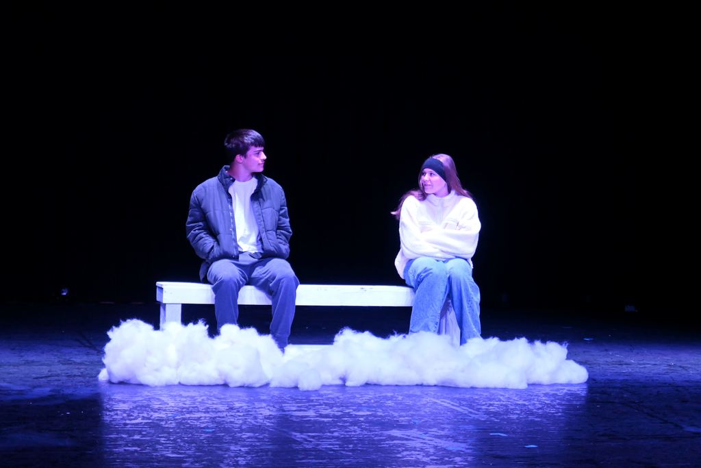 A  man and a woman  sit on a bench together.