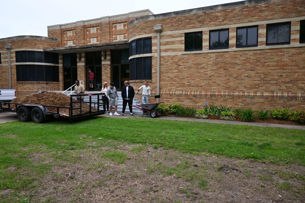 Students work to mulch beds in front of the city pool.
