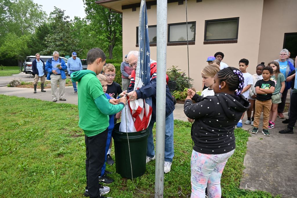 Pat McReynolds leads a small group of students in haningng the flags.