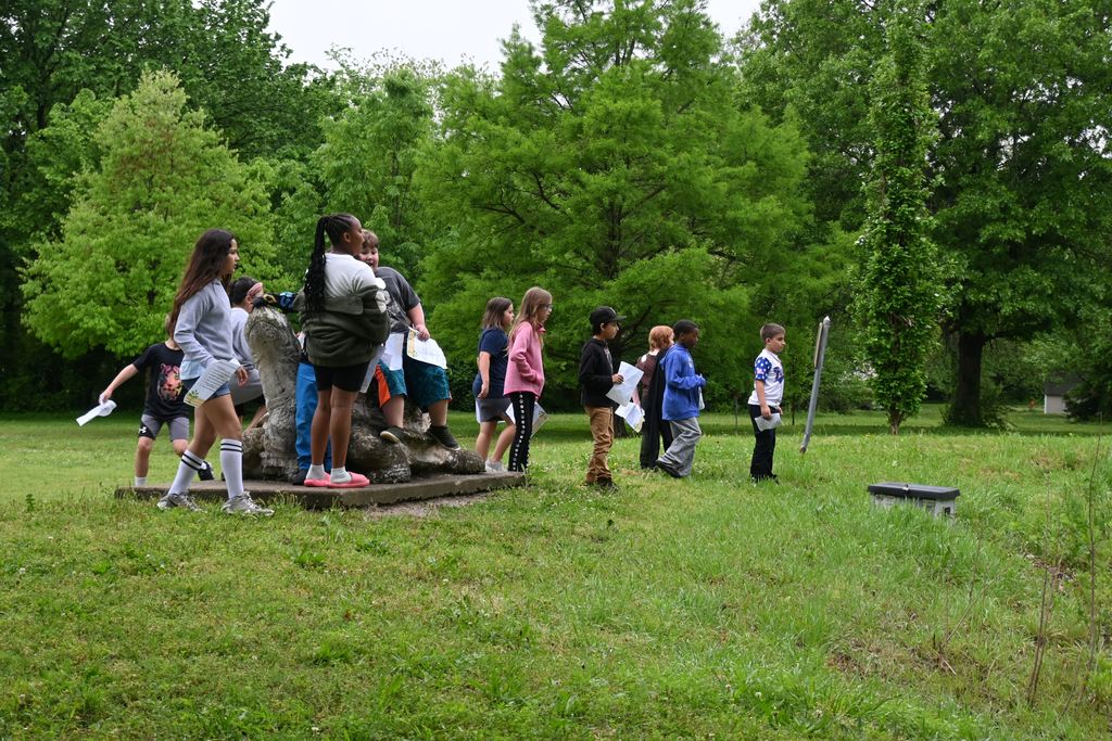 students climnb on top of the cement turtle.