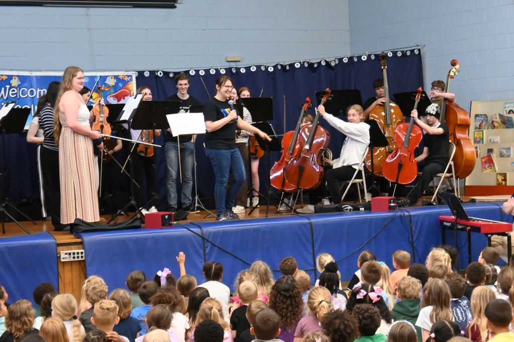 Cello players hold up their instruments.