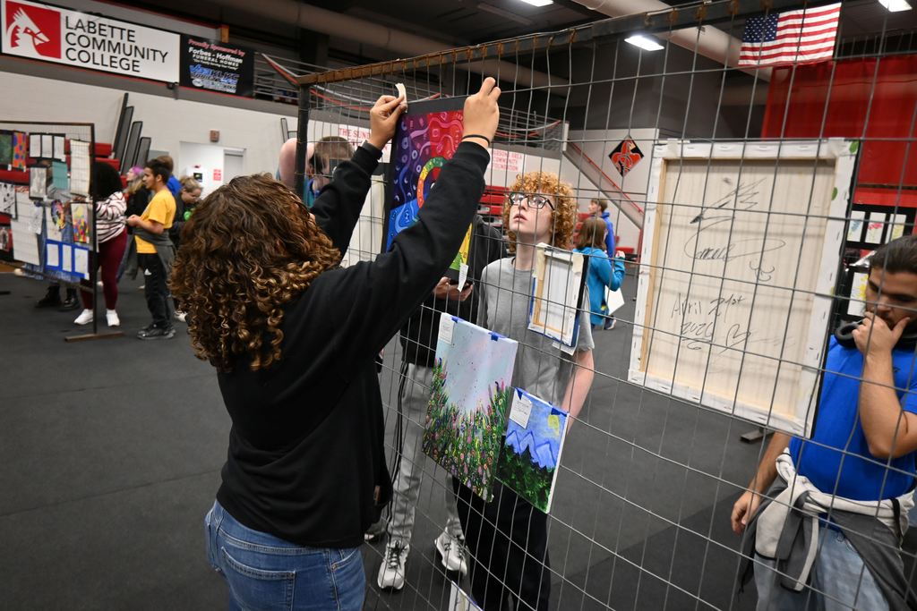 Students hang their art.