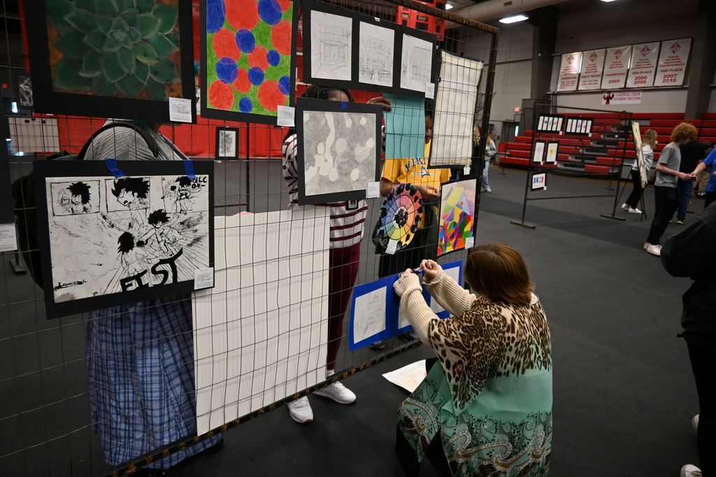 A student hangs her drawing.