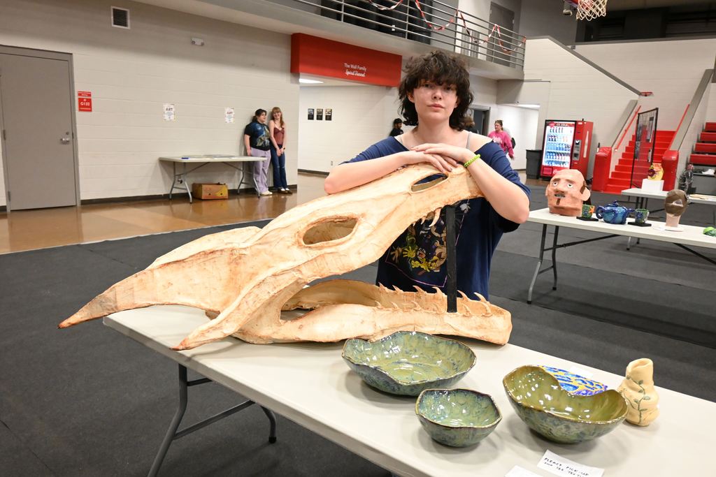A student stands with his dragon sculpture.