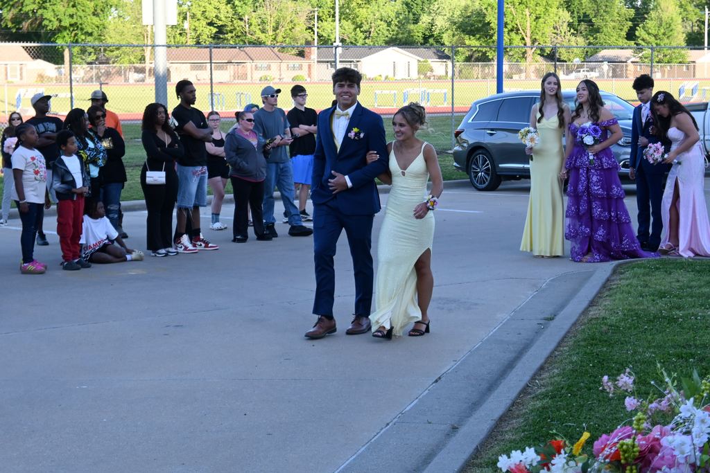 A boy escorts a girl into prom.