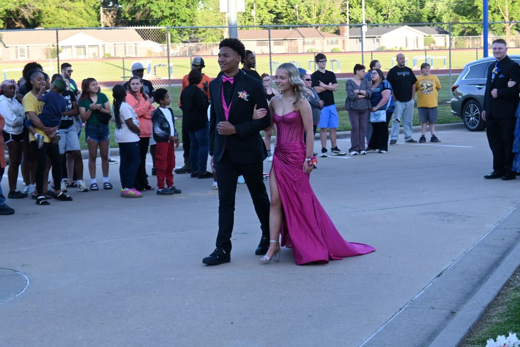 A boy escorts a girl into prom.