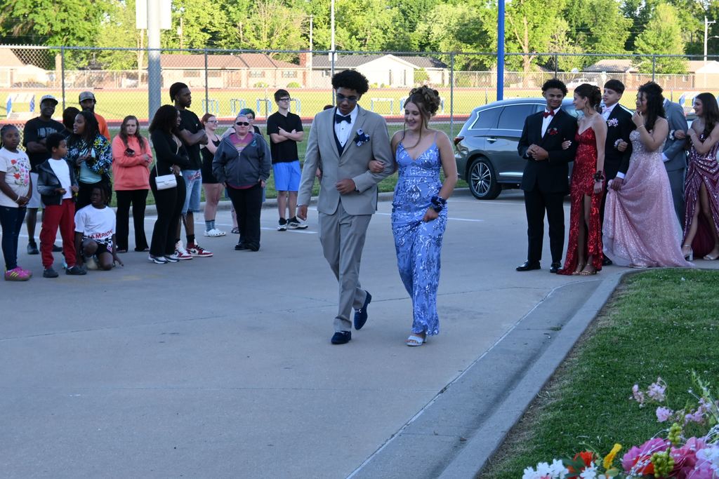 A boy escorts a girl into prom.