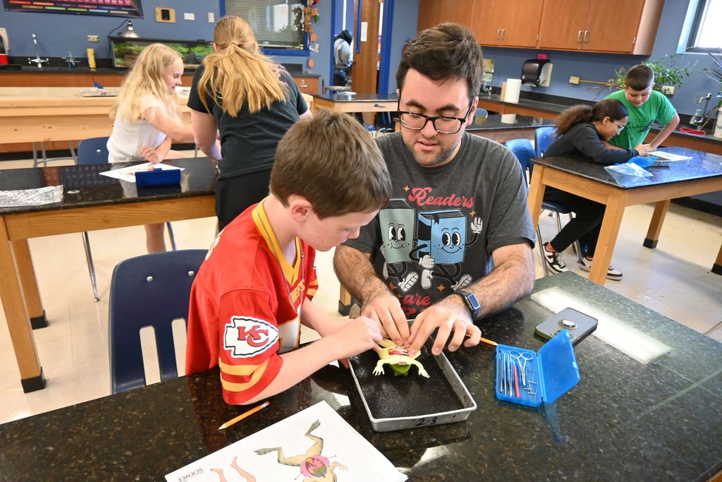 Mr. Holmes and a student work together to dissect a frog.