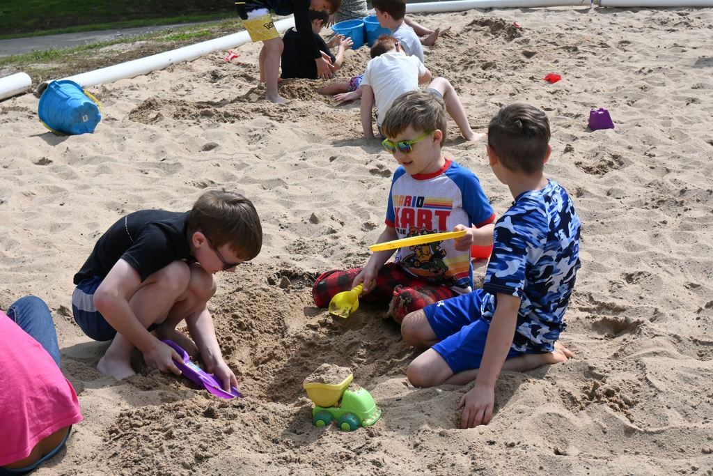 Three boys dig in the sand.