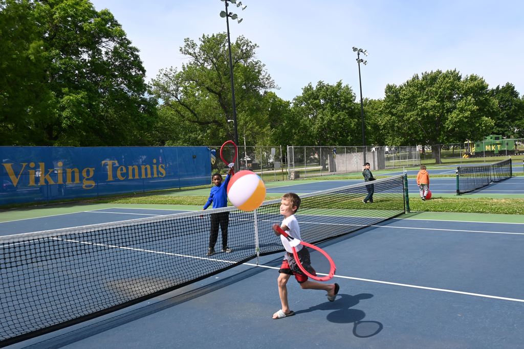 Two boys play tennis with beach balls.