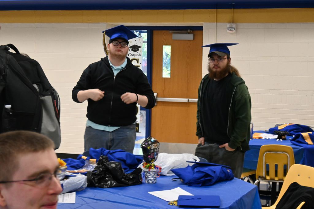 Two boys wear grad cap over their baseball caps.