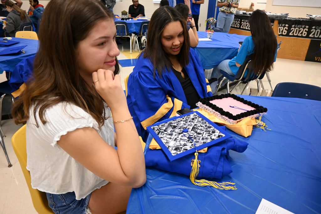 Their decorted graduation caps before them, two seniors wait for breakfast to begin.