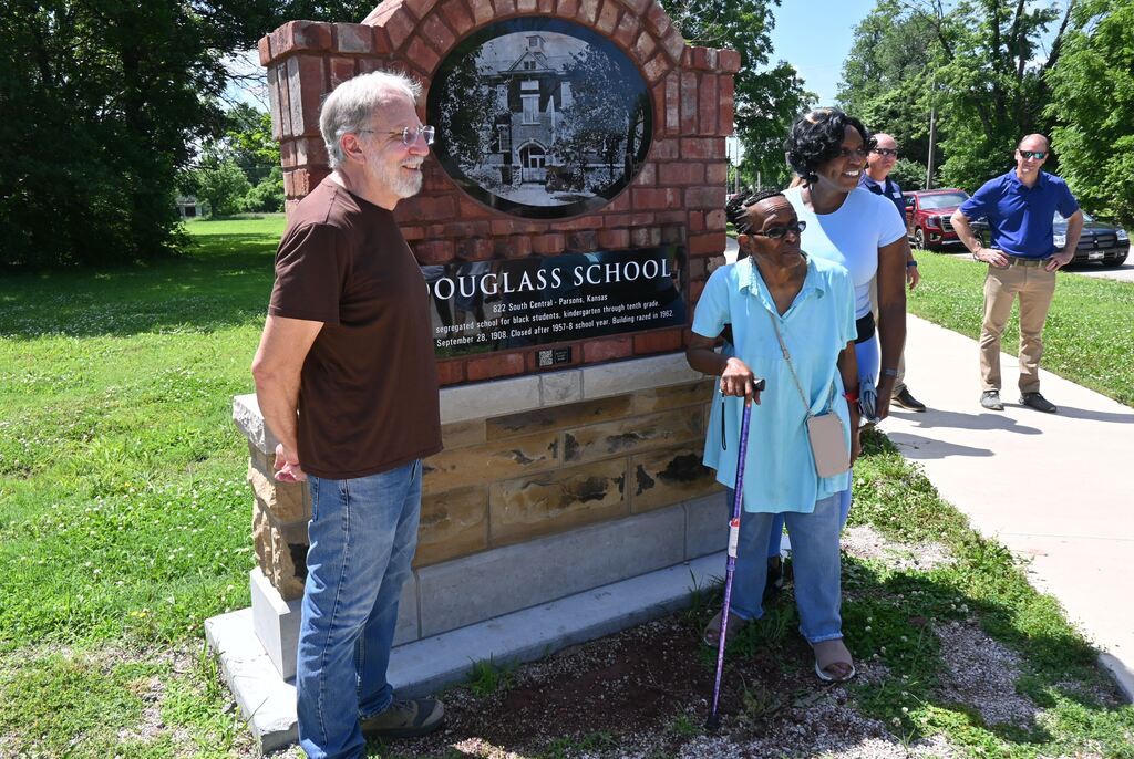 Jim Kutz gets his picture taken with the memorial he designed and former student Delphia Davis.