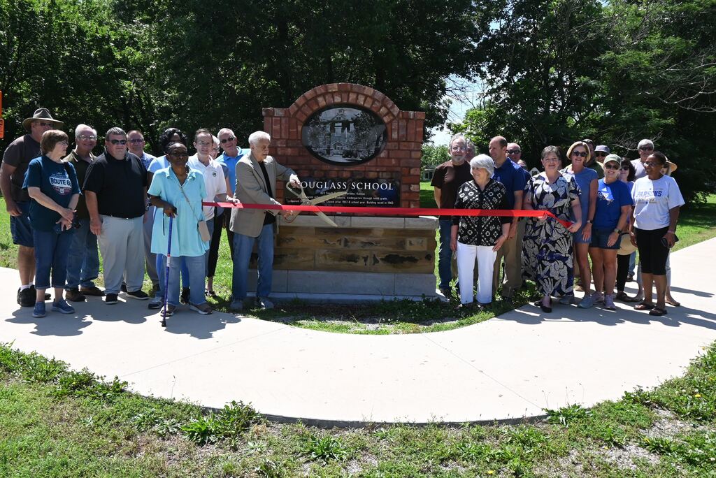 Parsons Chmaber of Commerce members, City Commissioners, USD 503 Administration and Board of Education and staff and attendees of the school get their picture taken cutting the ribbon.