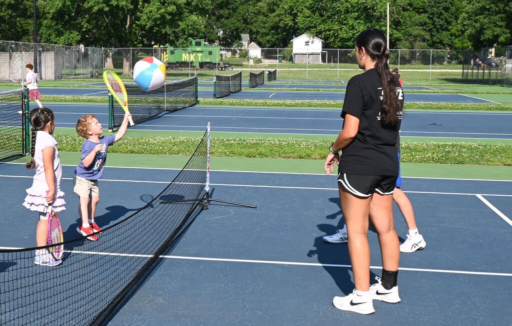 A little boy returns the beach ball with his racquet.