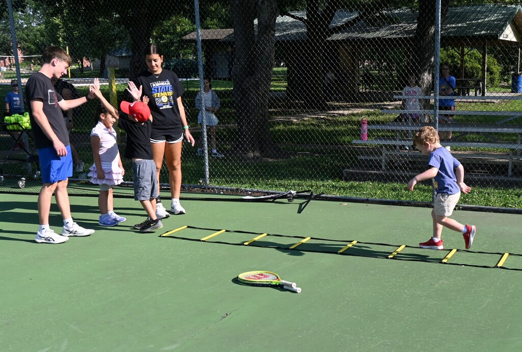 A little boy gets high fives from his teachers after running the ladder.