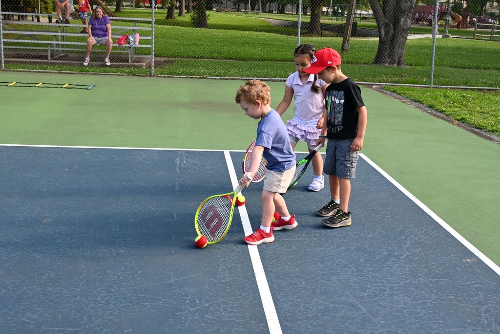 children use their racquets to push tennis balls across the court helping them learn control of the ball and their racquet.