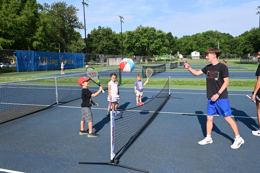 Children volley a beach ball to practice racquet skills.