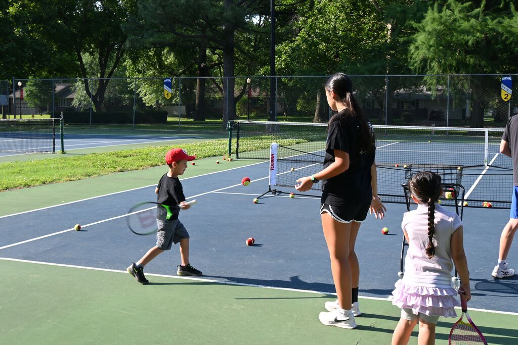 A little boy practices his forehand skills with his teacher,