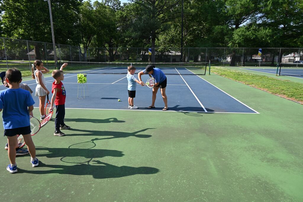 Halee Kennett helps a little boy with how to hold his racquet.