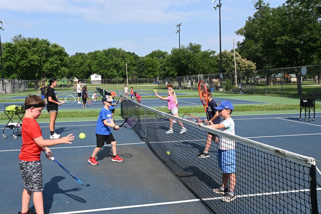 children practice volleying the ball over the net.