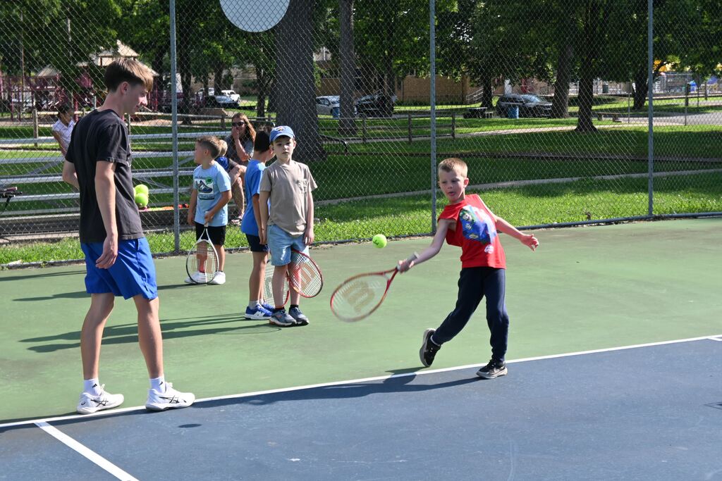 A boy swings at the tennis ball set up for him.