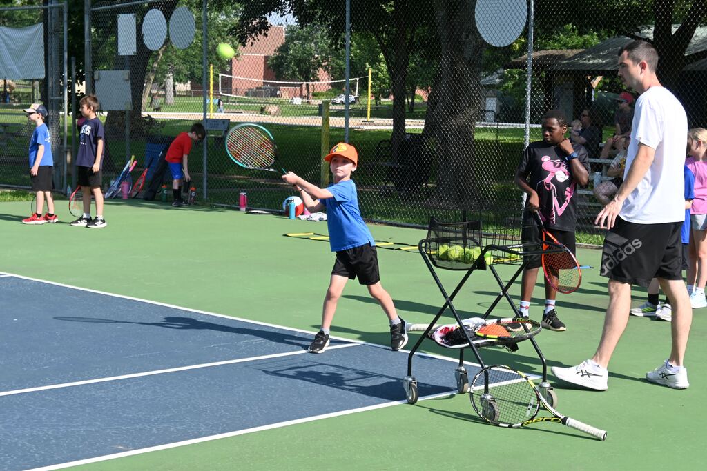 A boy hits the tennis ball.