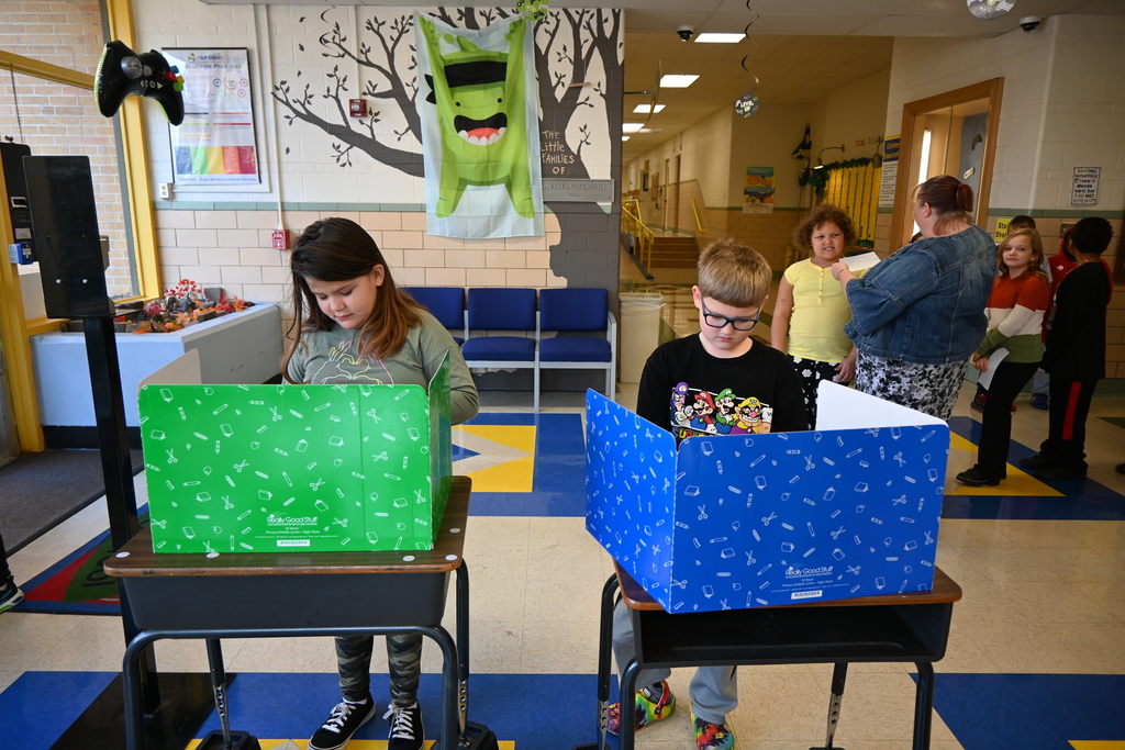 A girl and a boy fill out their ballots.