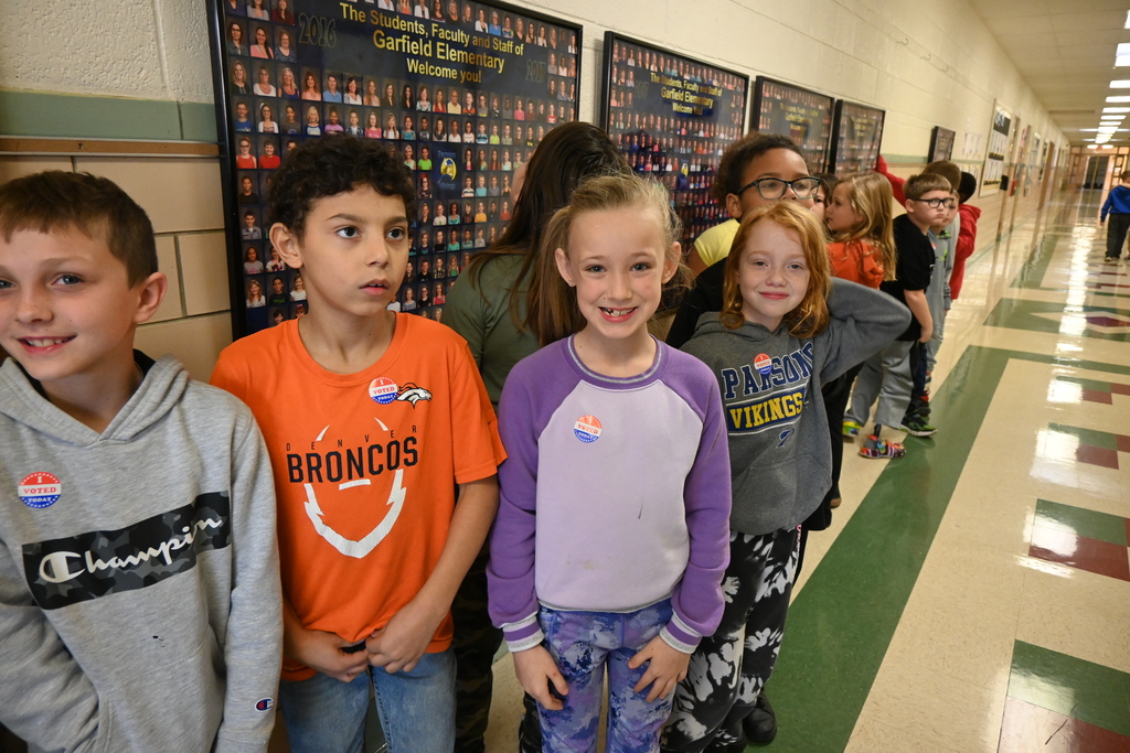 Students stabd n line and show their I Voted stickers.
