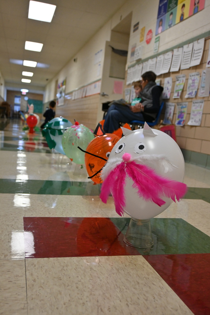 A balloon decorated like a kitty with feather whiskers.