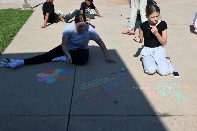 Students draw pictures and write quotes in chalk .