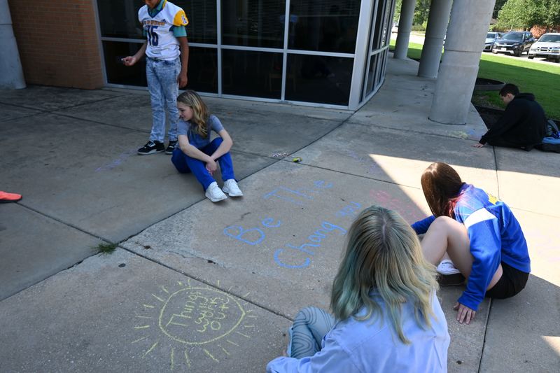 Students draw pictures and write quotes in chalk .