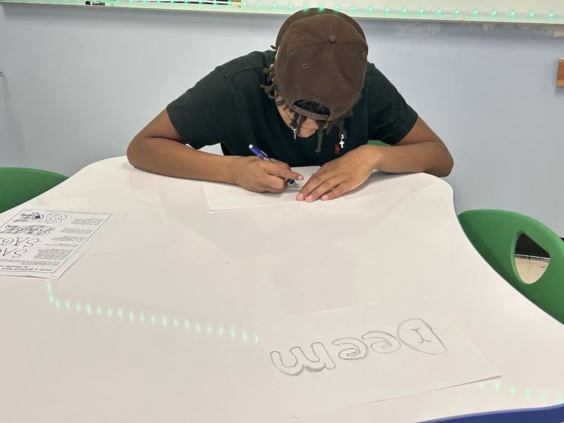 A young man writes graffiti words for a mural.