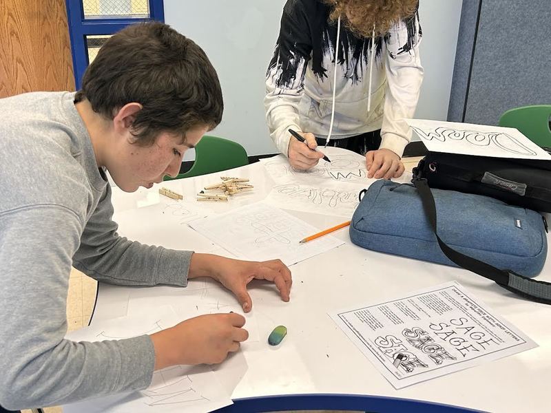 Two boys write their names and words in graffiti tag style.