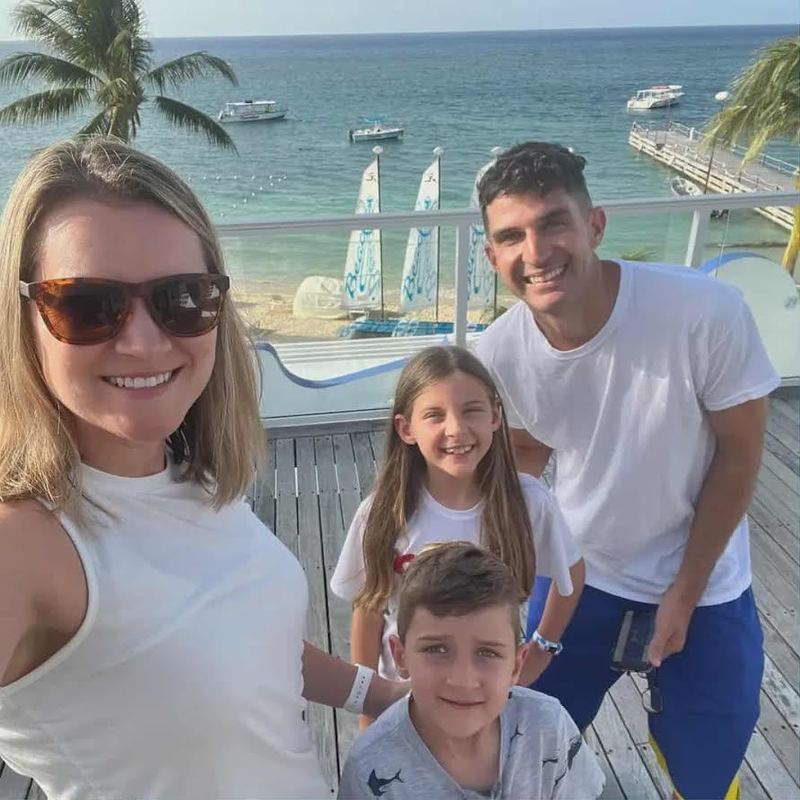 Nate Smith and his family near a beach with sailboats in the water.
