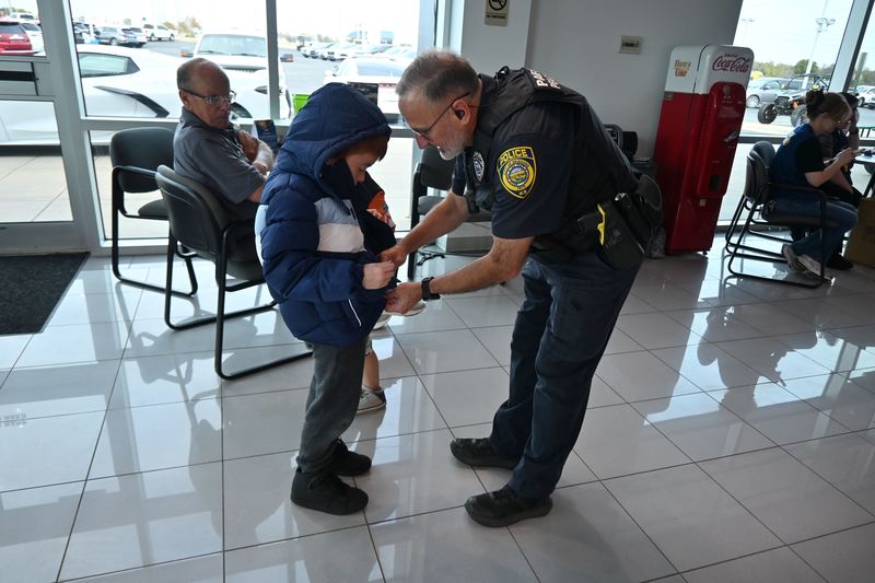 Officer Mark Raney helps a student with his coat.