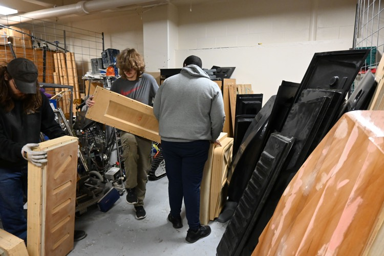 Three students organize molds for the Humvee in the storage area. 