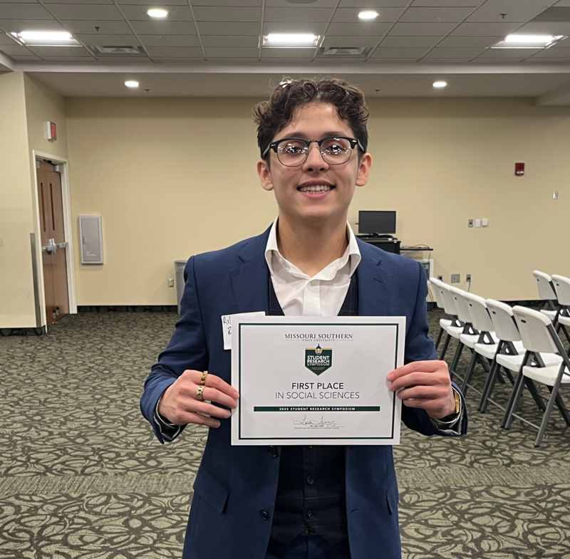 Ramirez hiolds up his first place certificate for his research project.