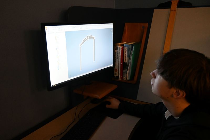 A student looks at his drafting drawings of an arch for the Arboretum.