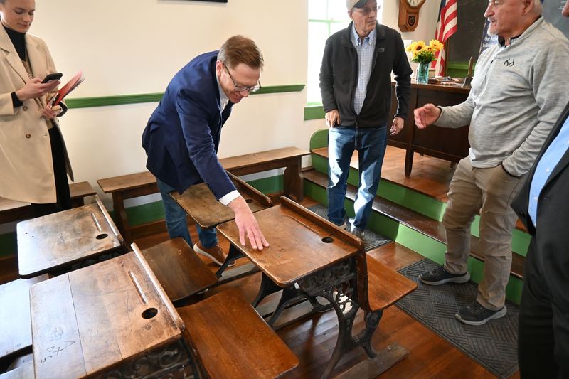Toland runs his hand across a desk engraved with a students initials.