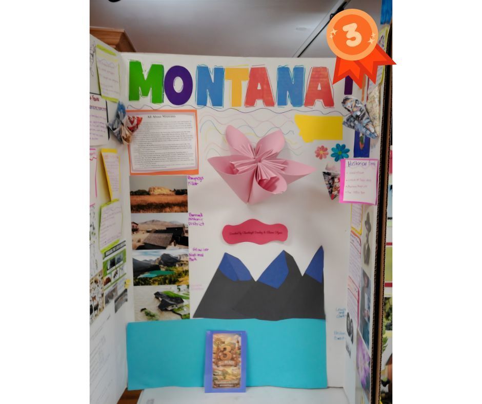 Tri-fold presentation board titled “Montana,” marked with a third-place ribbon icon in the top right corner. The display features colorful cut-out letters spelling Montana, typed research sections, and photos of Montana landscapes and landmarks. Decorative elements include paper butterflies, flowers, and a large pink folded paper flower in the center. The lower portion shows a layered paper scene of mountains and water. The project is neatly organized and creatively designed to highlight Montana’s geography, history, and attractions.