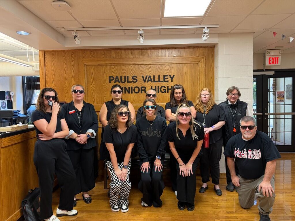 Ten PVJH staff members pose in the school lobby dressed in black with sunglasses for an undercover Secret Service dress-up day.