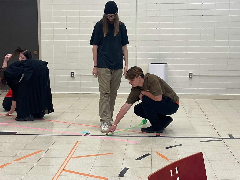 Students tape green and hot pink lines down to match the coordinates in their math problems.