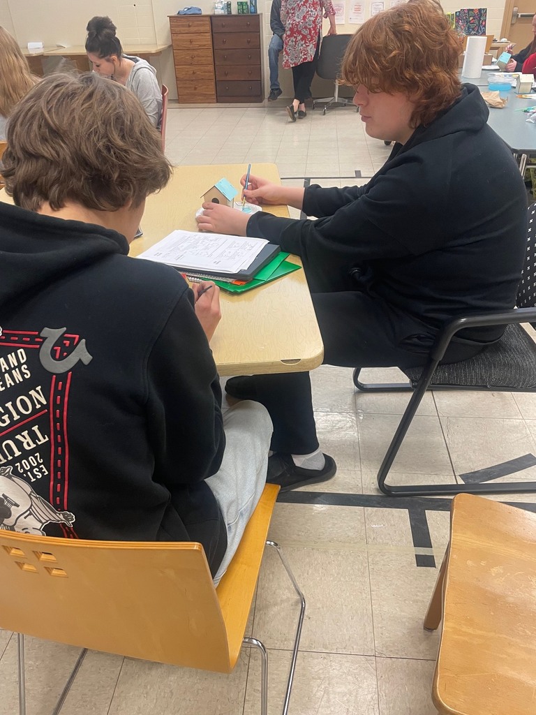 Two boys working on painting bird houses