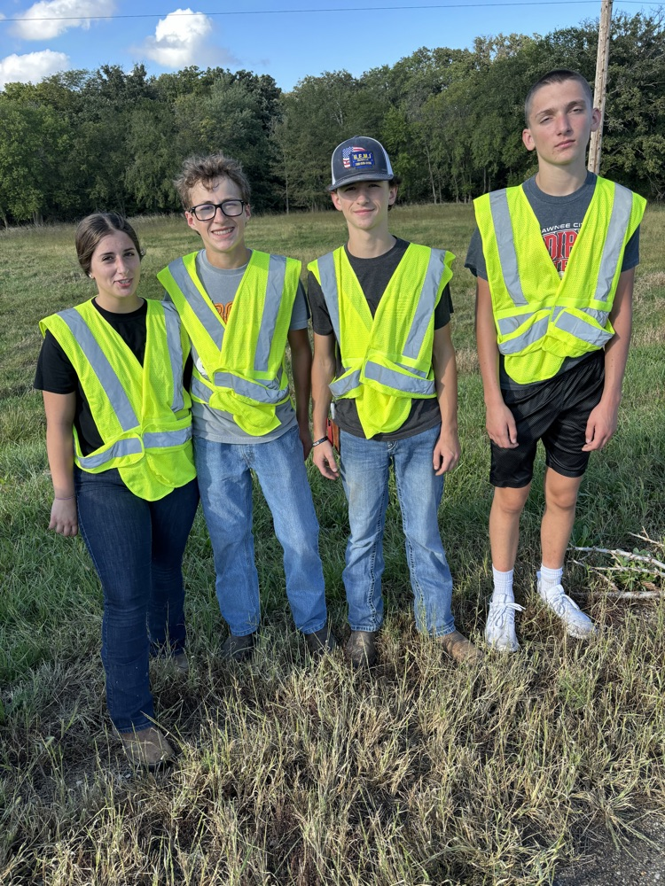 4 students in high visibility vests standing outside
