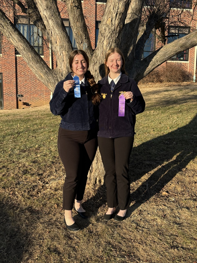 Morgann and Kailey standing with their ribbons next to a tree