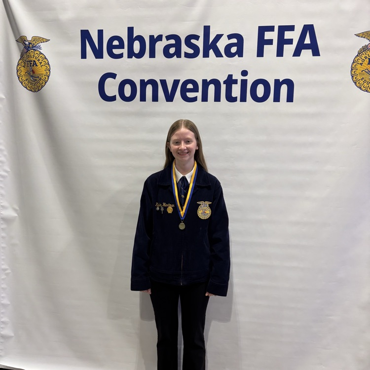 Kaily standing in front of a backdrop with her medal